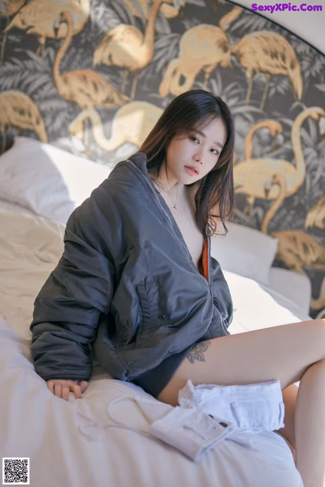 A woman sitting on top of a bed next to a wall.