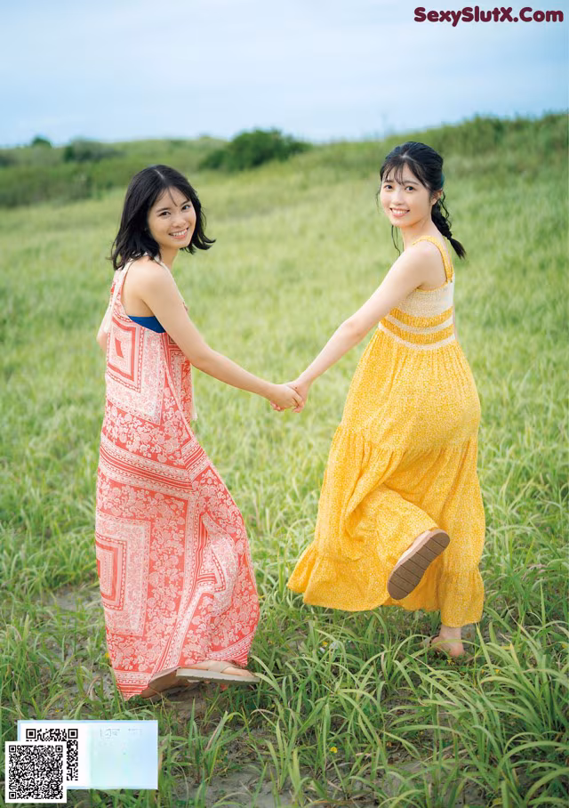 A couple of women holding hands in a field.