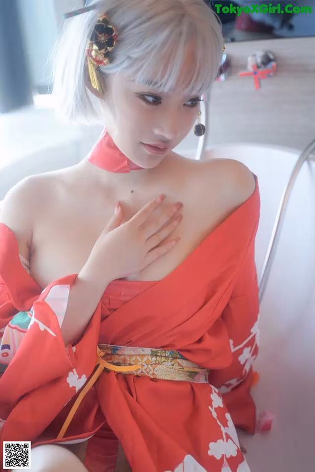 A woman in a red kimono sitting on a chair.