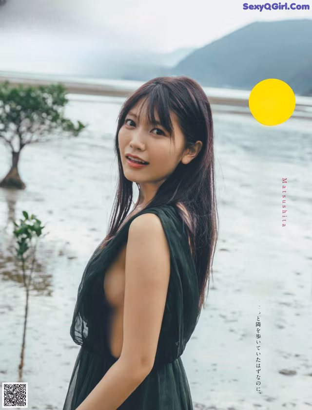 A woman in a black dress standing in the water.