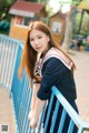 A woman in a school uniform leaning against a railing.