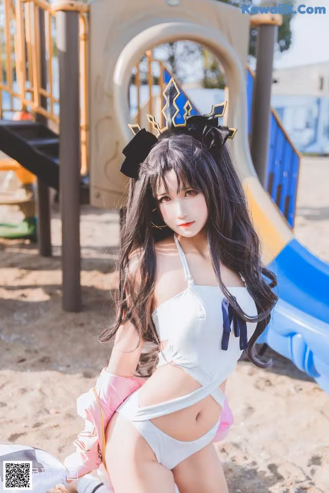 A woman in a white bikini sitting on a playground.