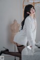 A woman in a white shirt and black stockings posing for a picture.