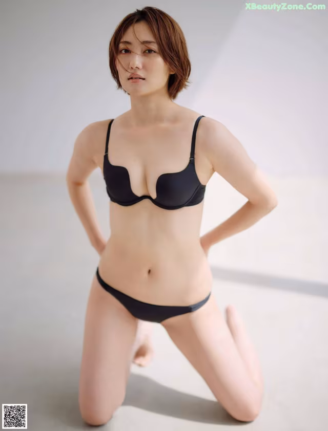 A woman in a black bra and panties posing for a picture.