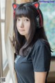 A woman wearing a black shirt and a pair of cat ears.