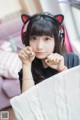 A young woman wearing a pair of cat ears and headphones.