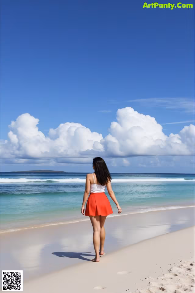 A woman walking on a beach near the ocean.
