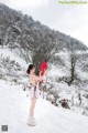 A woman in a pink dress holding a red heart in the snow.