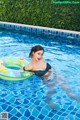 A woman in a bikini laying on an inflatable ring in a pool.