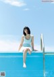 A woman sitting on the edge of a swimming pool.