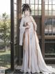 A woman in a white dress standing in front of a window.
