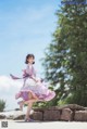 A woman in a purple dress is dancing on a stone wall.