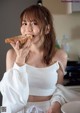 A woman eating a piece of bread in a kitchen.