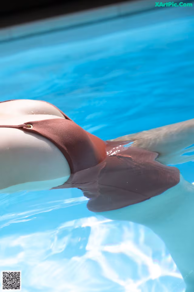 A woman in a brown bikini floating in a pool.