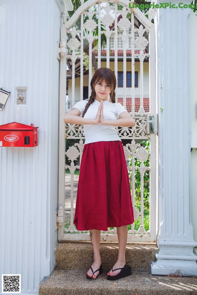 A woman standing in front of a white gate.