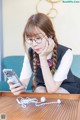 A young woman sitting at a table looking at her phone.