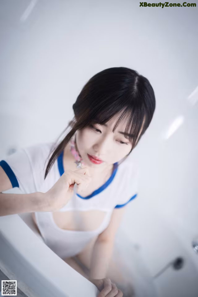 A woman sitting in a bathtub with her hand on her chin.