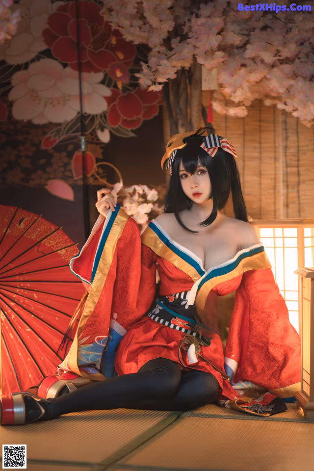 A woman in a red kimono sitting on the floor with an umbrella.