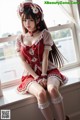 A woman in a red and white dress sitting on a window sill.