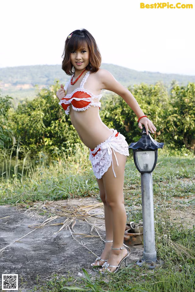 A woman in a red and white bikini posing next to a lamp post.