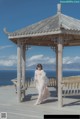 A woman in a white dress standing under a gazebo.