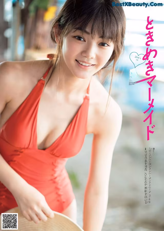 A woman in a red bathing suit holding a straw hat.