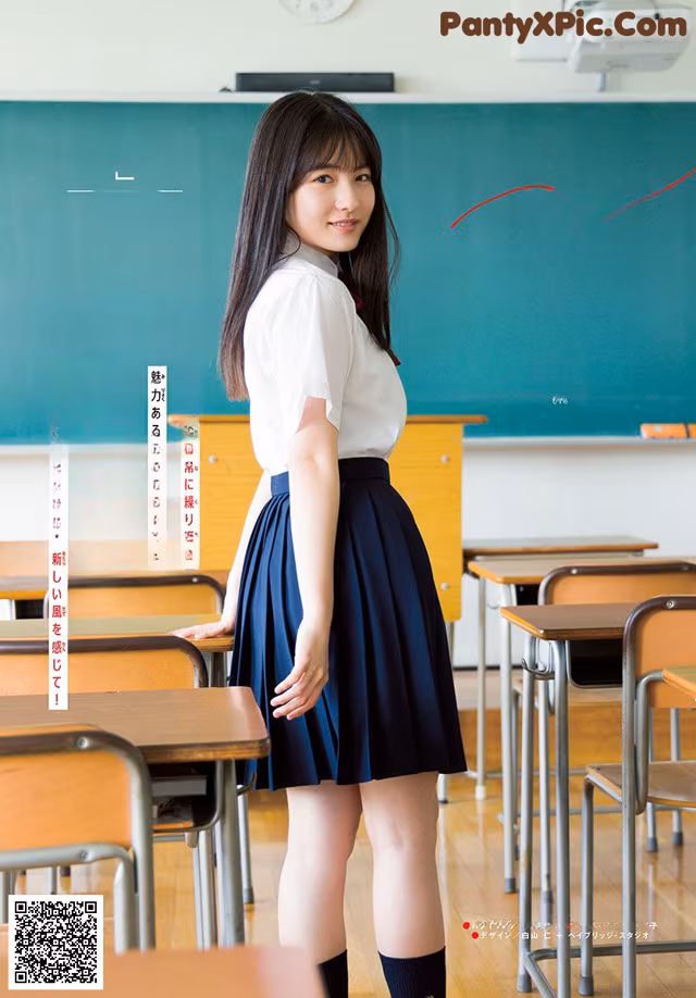 A woman in a school uniform standing in front of a blackboard.