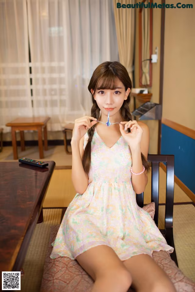 A woman sitting on a chair holding a toothbrush in her mouth.