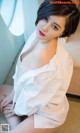 A woman in a white shirt sitting on a couch.