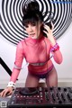 A woman in a pink top and fishnet stockings playing a dj set.