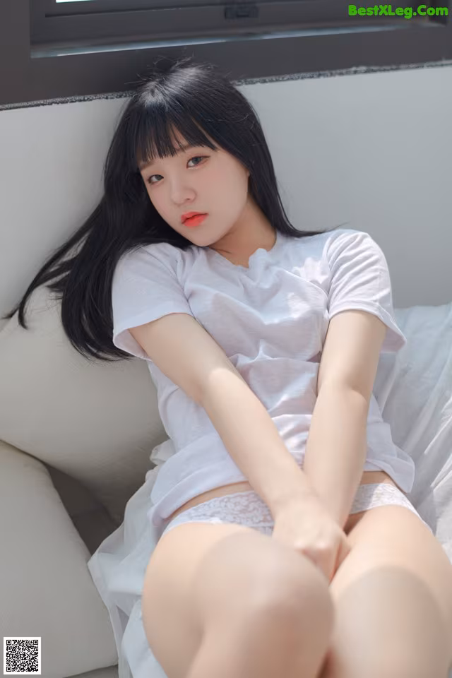 A woman sitting on top of a white couch.